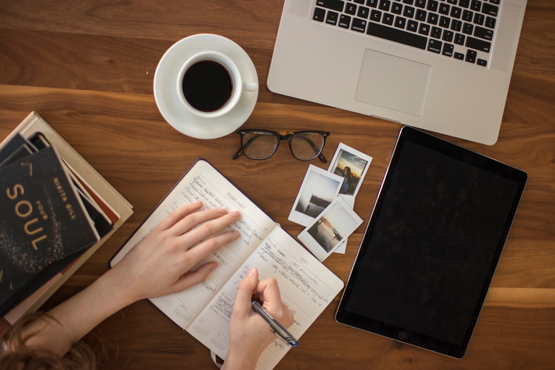 Person writing intentions in journal with focused, determined expression in peaceful setting