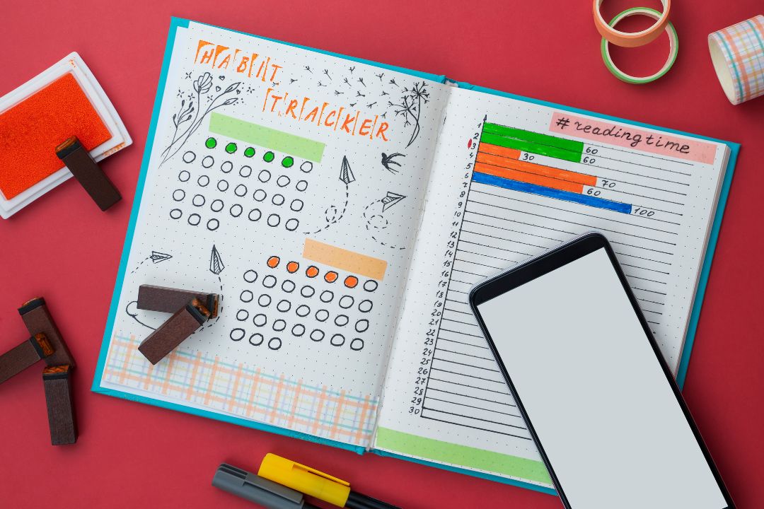 person writing habit tracker journal success building consistency