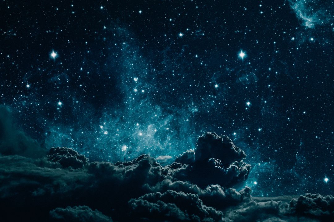 Person sitting peacefully in darkness with gentle light representing dark night of the soul spiritual growth